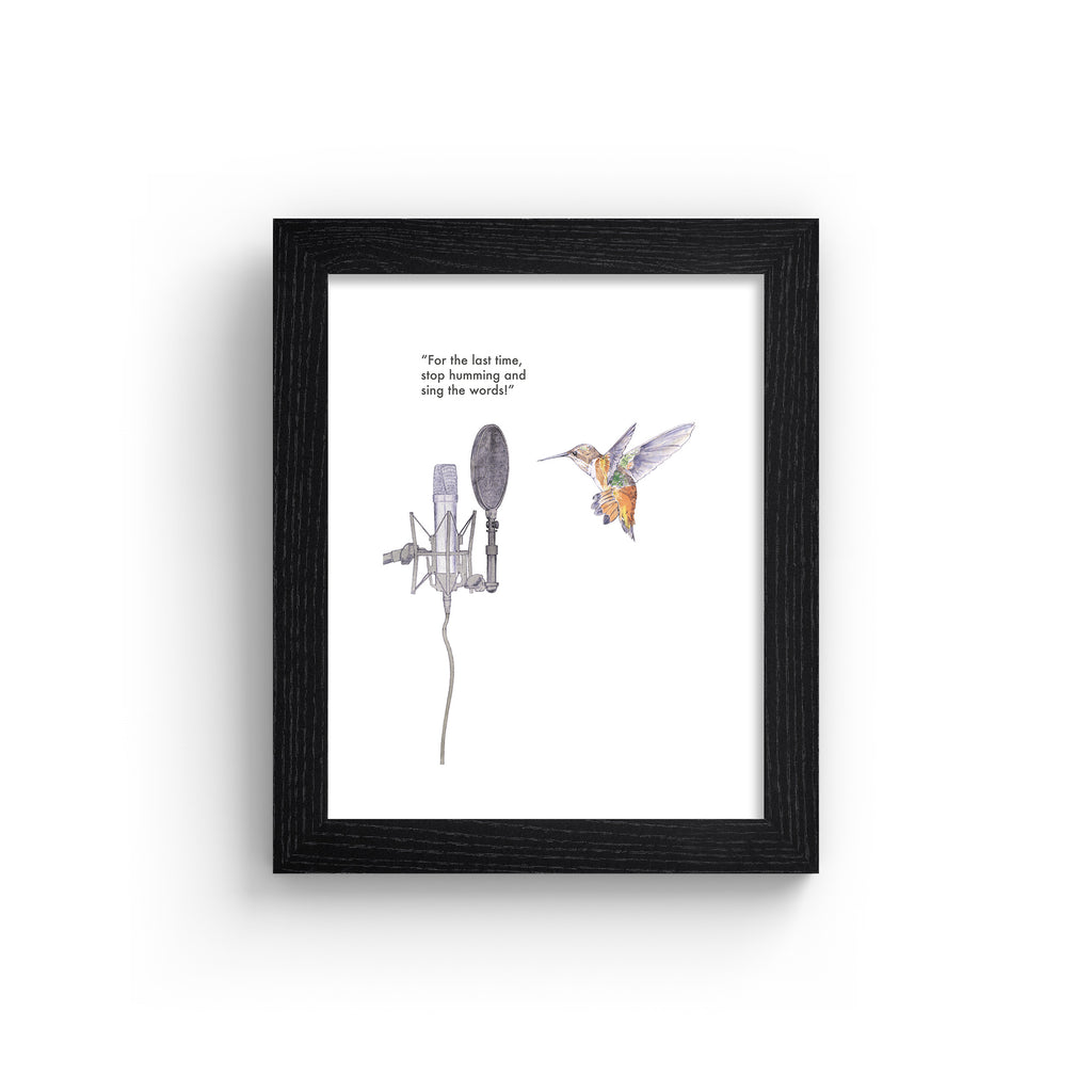 Humorous art print featuring an illustration of a hummingbird in front of a microphone. Text line reads 'For The Last Time, Stop Humming And Sing The Words!'. Art print is in a black frame.