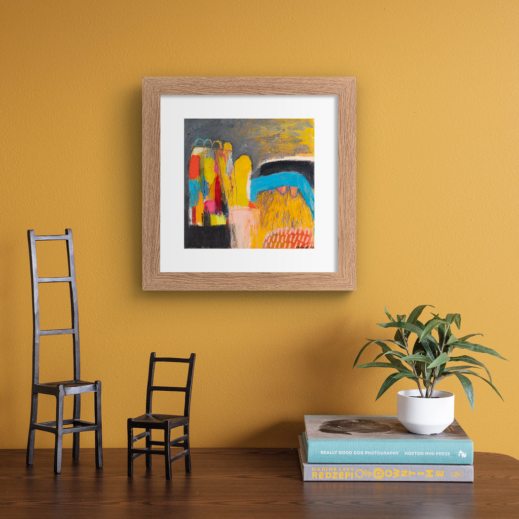 Vivid abstract print featuring an urban array of mixed colours on a dark background. Art print is hung up on an orange wall.