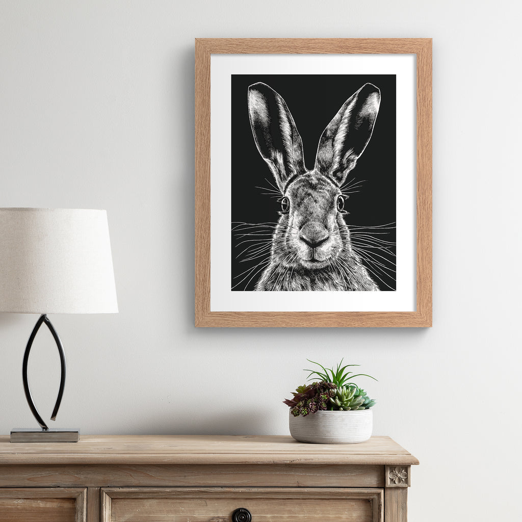 Striking art print featuring a detailed illustration of a wild hare, in black and white. Art print is hung up on a beige wall.
