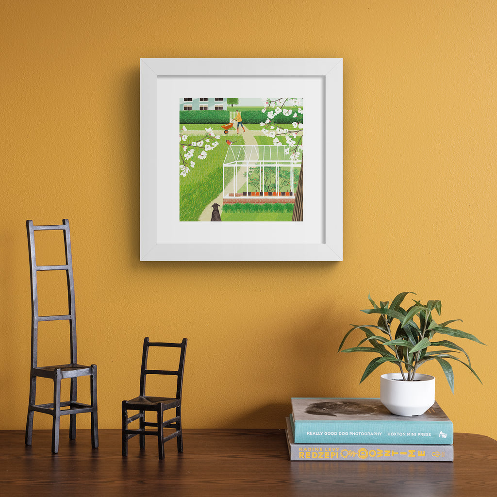 Beautiful art print featuring two characters in a vibrant green garden. Art print is hung up on an orange background.