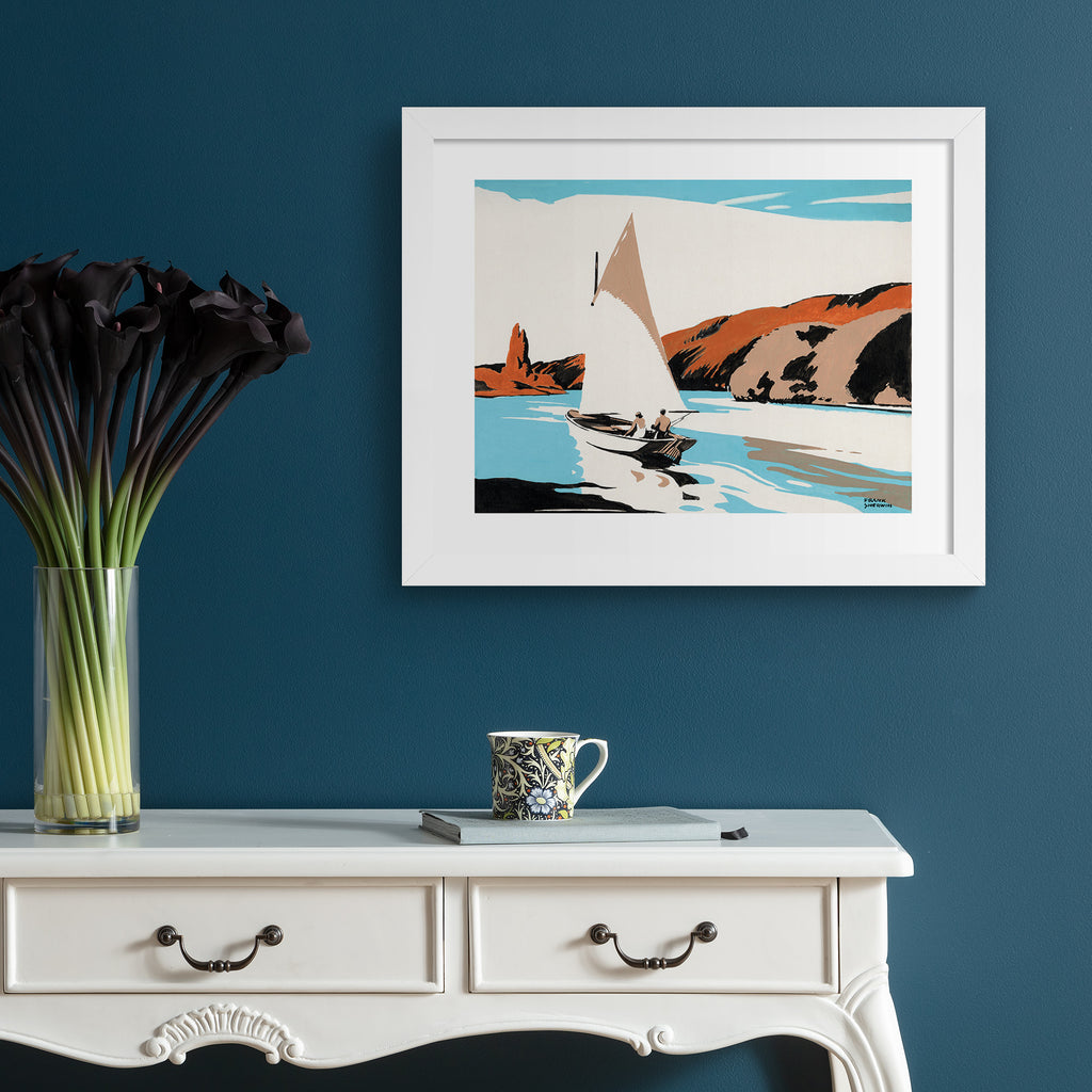 Classical watercolour art print featuring a sailboat heading along a shore, hung up on a blue wall.